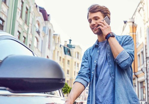 Mann steigt in sein Auto und telefoniert.