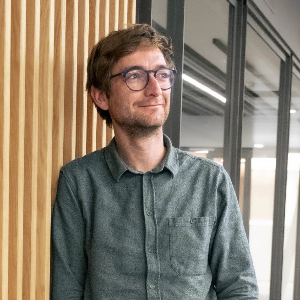 Tim lehnt an einer Holzwand