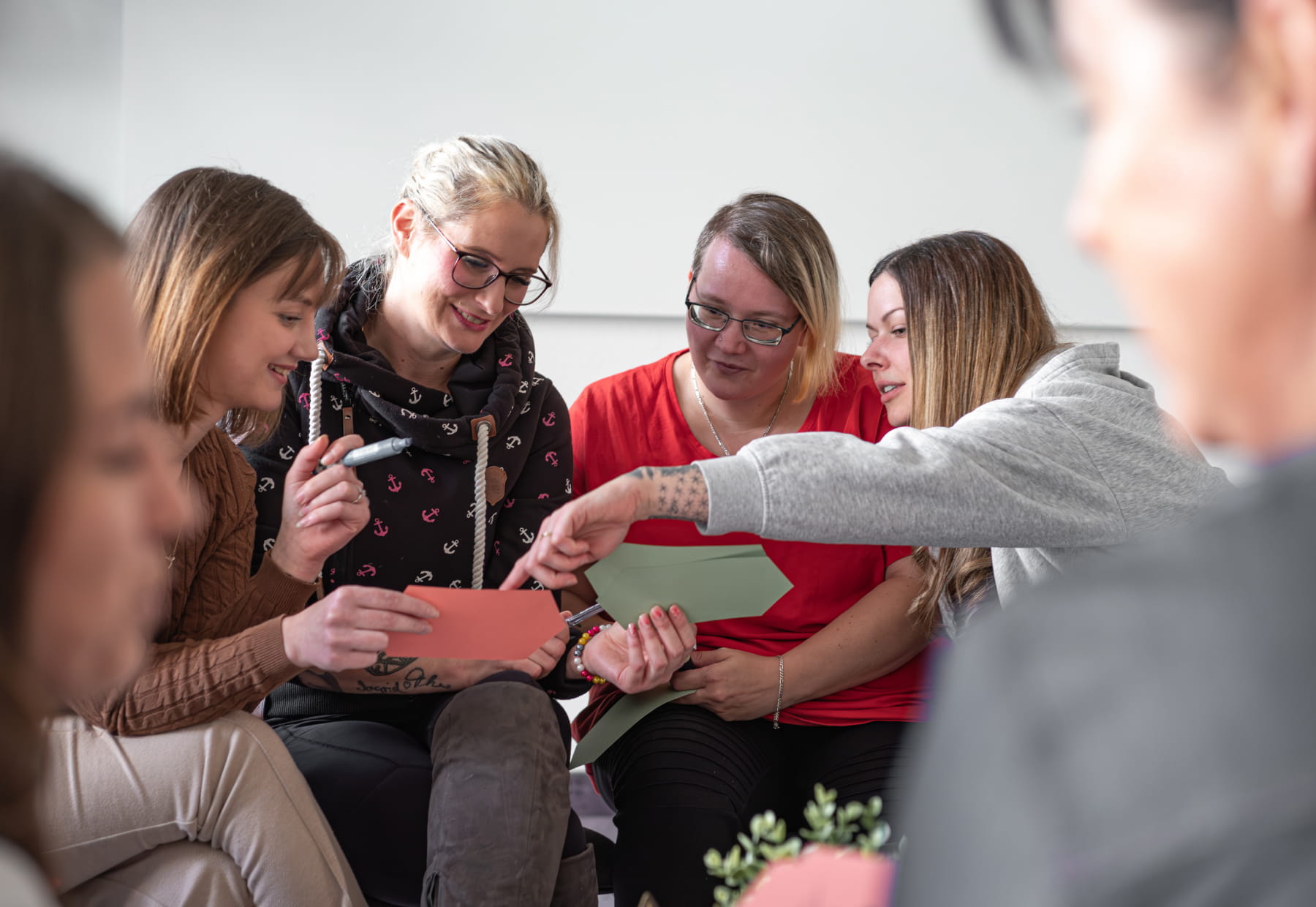 Personen sitzen zusammen und tauschen sich mit farbigen Karten aus. 