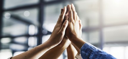 Vier Personen klatschen sich in der Luft ab