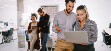 Bürosituation: zwei Frauen und zwei Männer schauen in den Laptop.