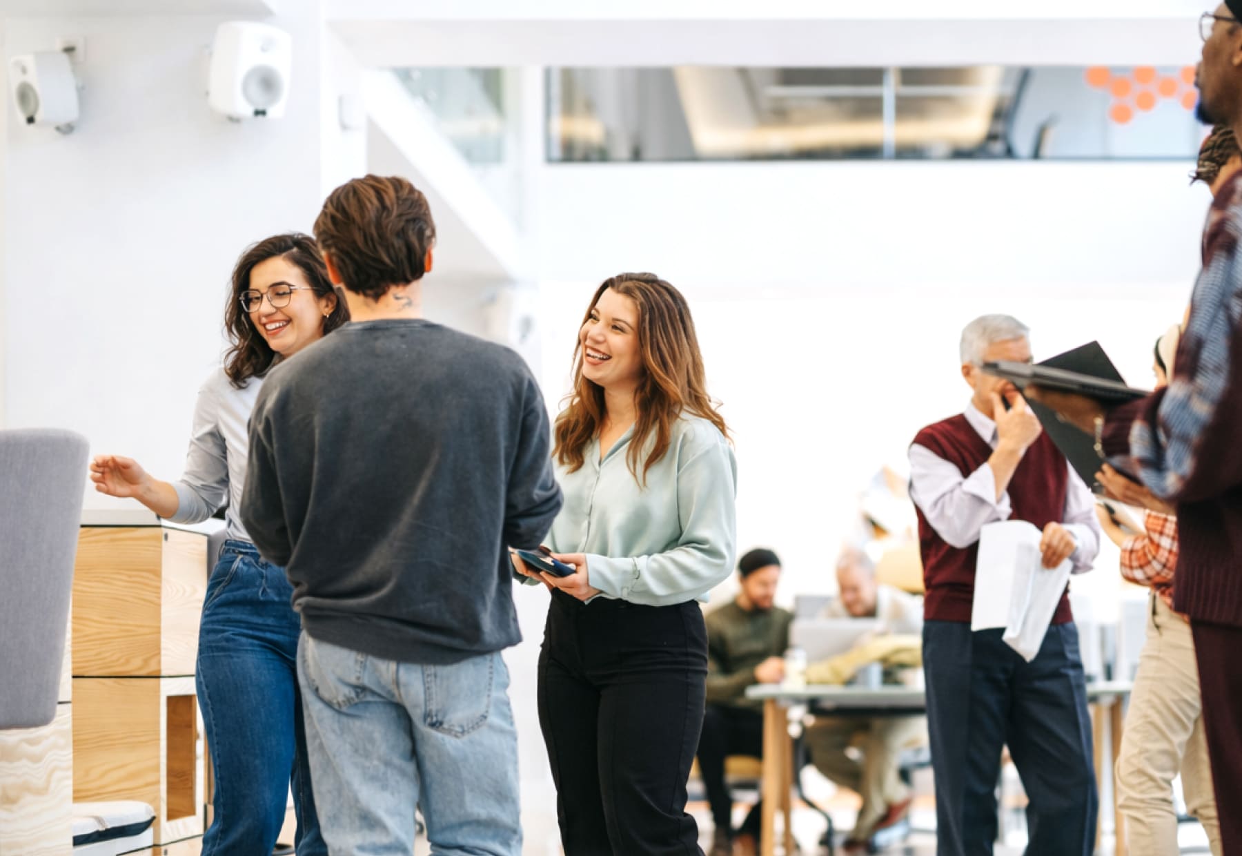 Mehrere Personen stehen und unterhalten sich in einem modernen, hellen Büro. Im Hintergrund sind Tische und Stühle zu sehen.