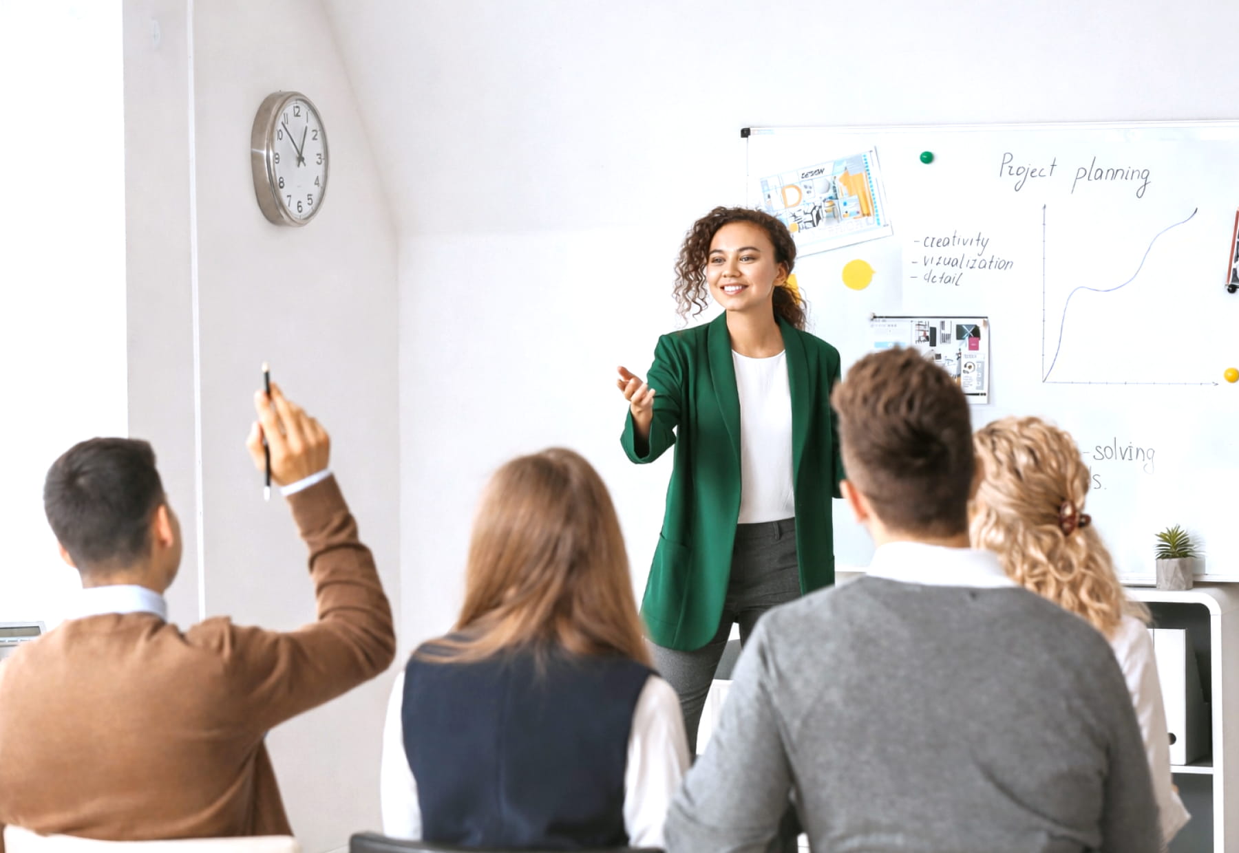 Eine Person präsentiert vor einem Publikum, während sie vor einer Tafel mit Diagrammen und Notizen steht.