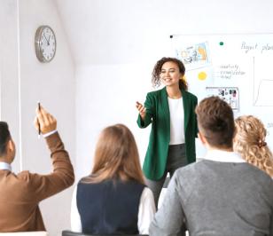 Eine Person präsentiert vor einem Publikum, während sie vor einer Tafel mit Diagrammen und Notizen steht.