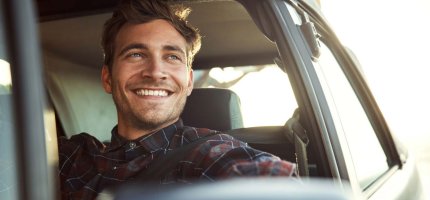 Mann im Auto lacht nach draußen durch das Fenster