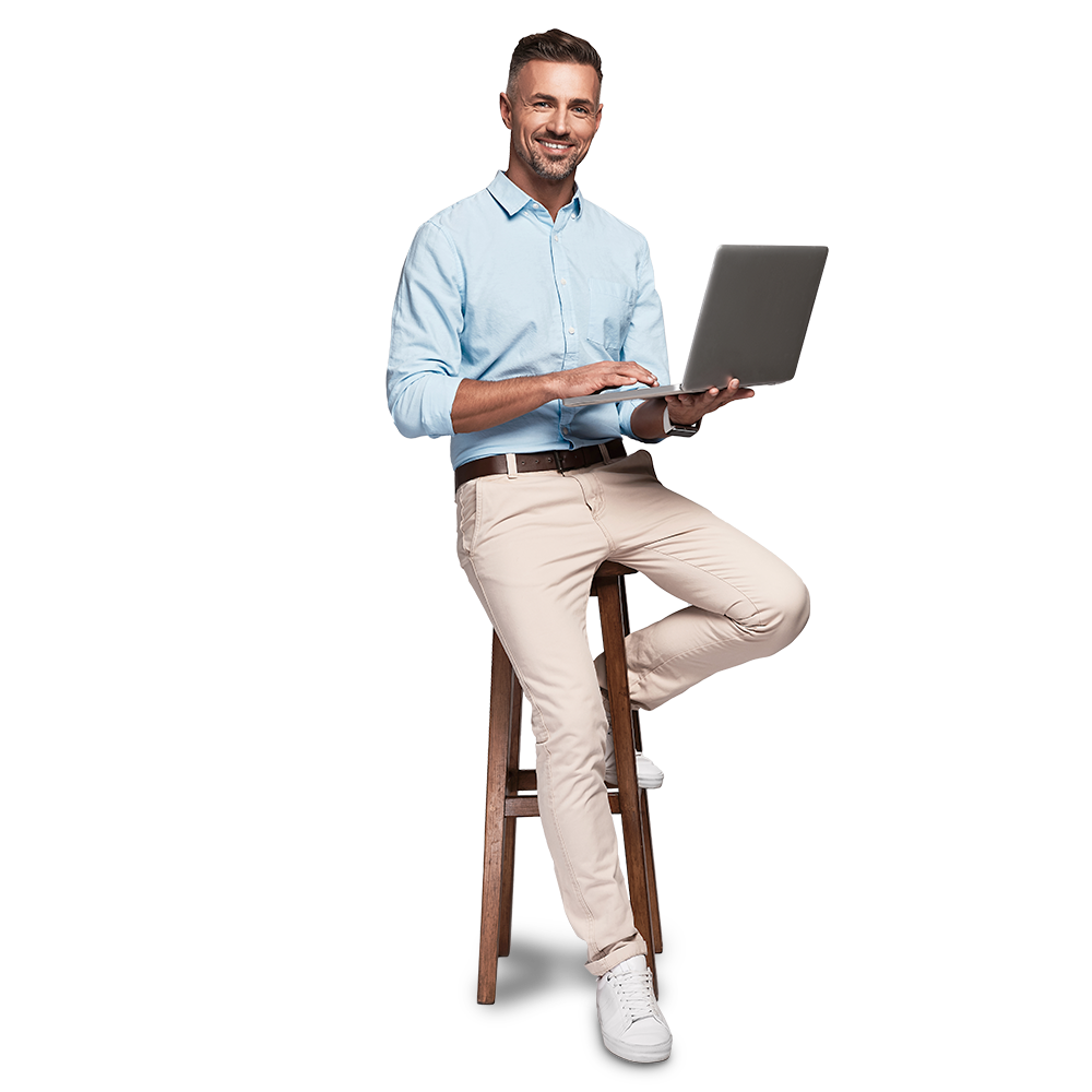 Mitarbeiter sitzt auf einem Hocker und arbeitet an einem Laptop.