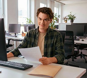 Beamtenanwärter sitzt an seinem Schreibtisch und bearbeitet Dokumente