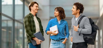 Zwei Beamtenanwärter und eine Beamtenanwärterin stehen in einer Eingangshalle und tauschen sich aus