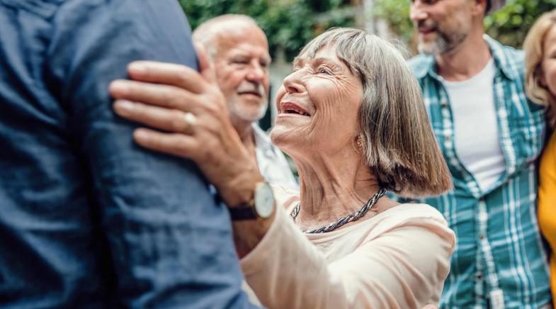 Eine Oma freut sich und hält Ihren Sohn am Arm.