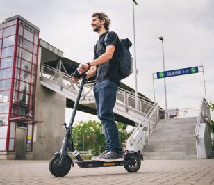 Mann fährt auf einem E-Scooter.