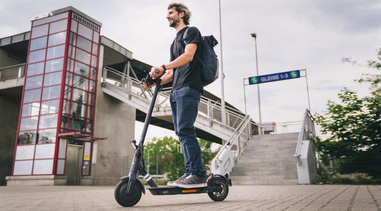 Mann fährt auf dem E-Scooter