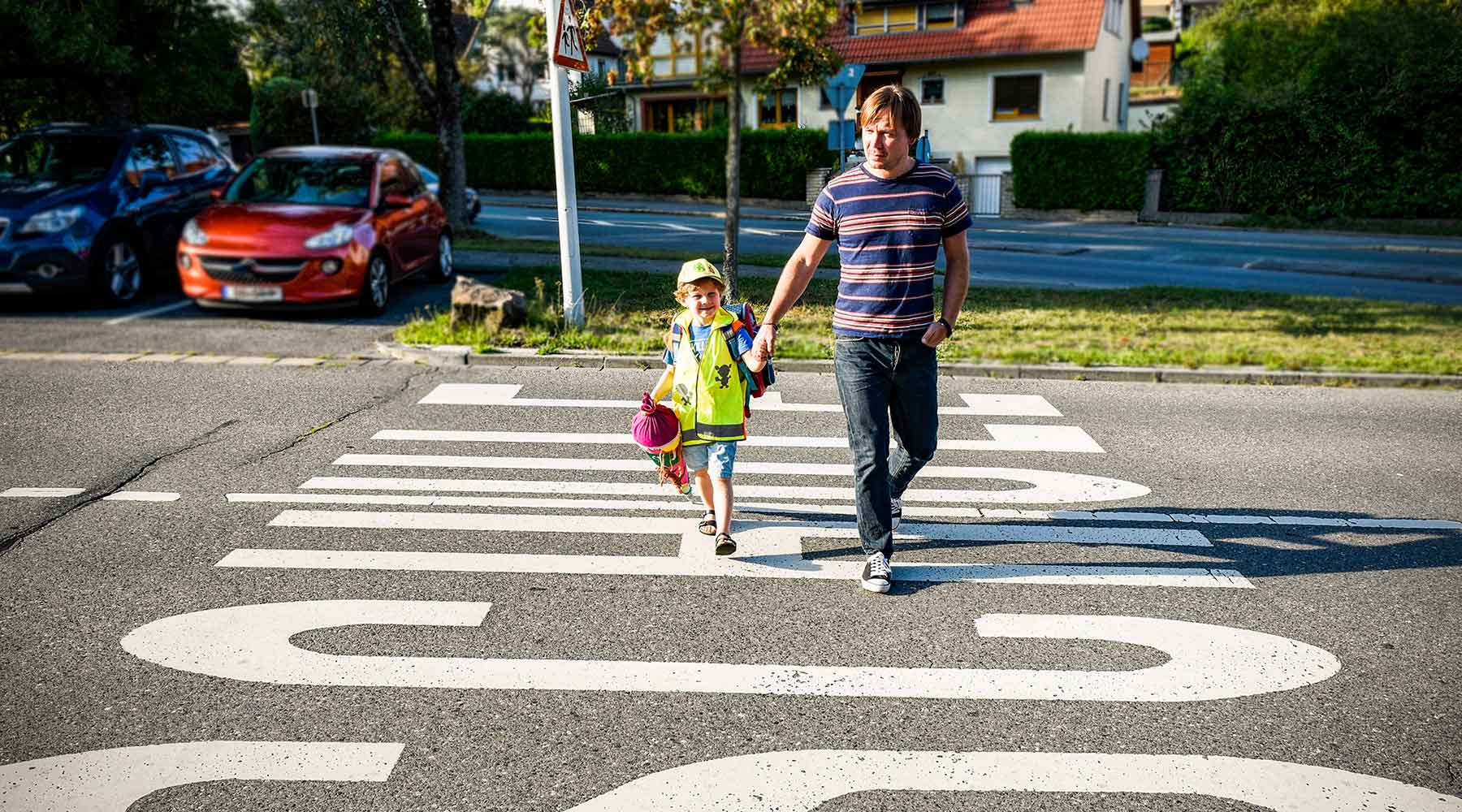 Vater bringt sein Kind über die Straße