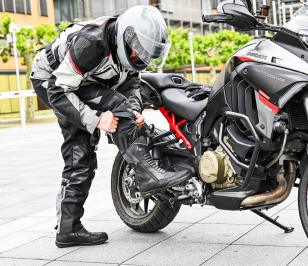 Mann in Motorradschutzkleidung steht neben Motorrad