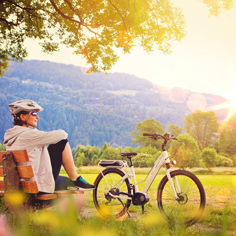Frau mit e-Bike genießt Sonnenuntergang