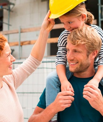 Eine Familie auf der Baustelle, der Vater hat das Kind auf den Schultern.