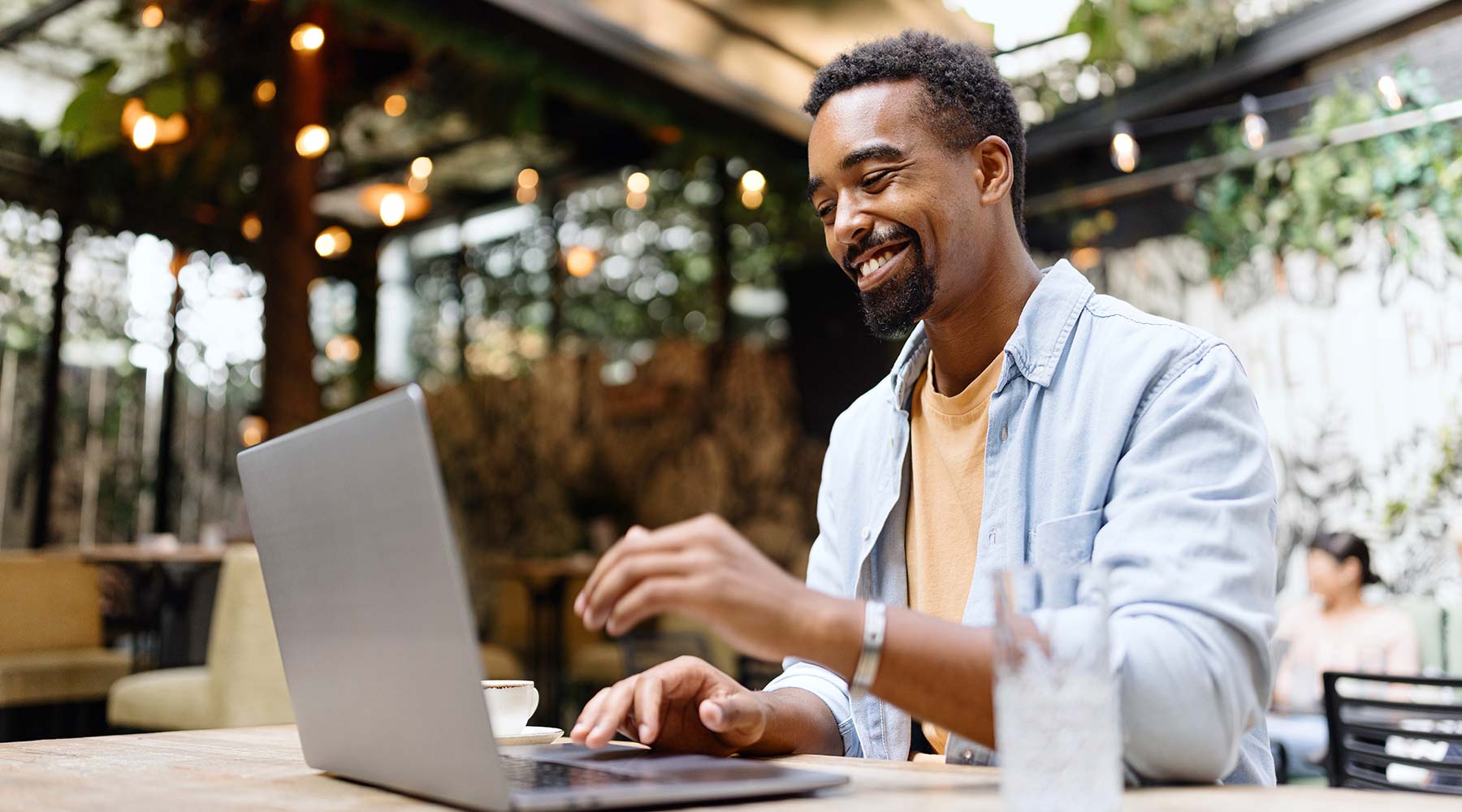 Ein junger Mann sitzt mit seinem Laptop in einem Kaffee.