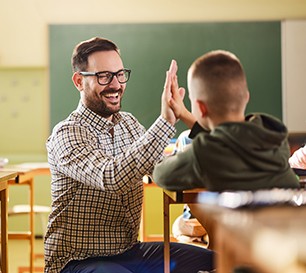 Junger Lehrer gibt einen Schüler High-Five.