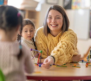 Junge Lehrerin bastelt mit zwei Grundschülerinnen.