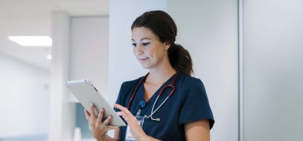 Junge Ärztin schaut im Krankenhaus auf ein Tablet.