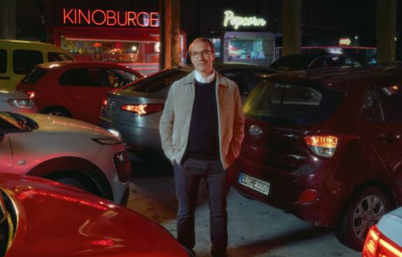 Herr Möller vor einer Reihe Autos im dunklen Autokino.
