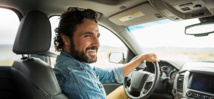 Lächelnder Mann hält die Hand seiner Frau während er Auto fährt.