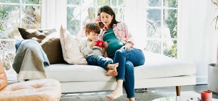 Frau sitzt mit ihrem Kind auf der Couch