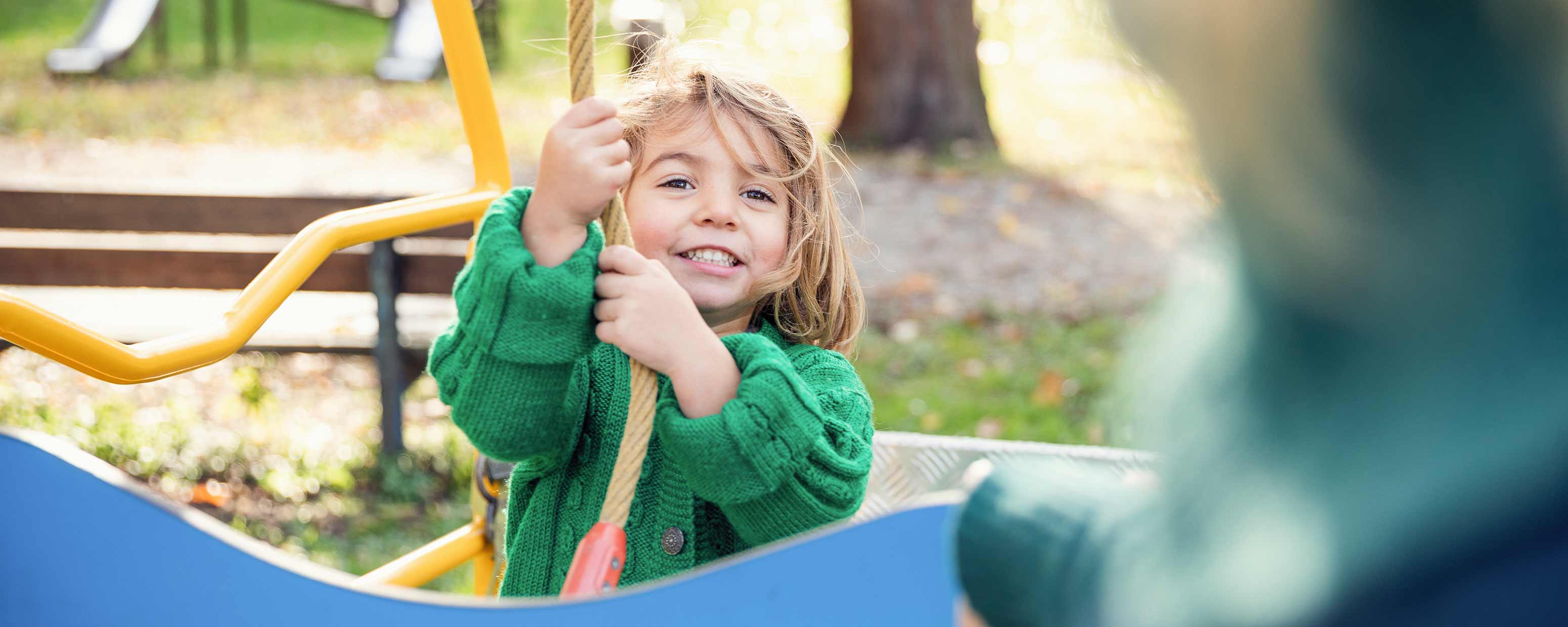 Ein Kind hält sich auf einem Spielplatz an einem Kletterseil fest.
