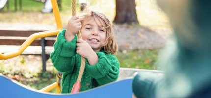 Ein Kind hält sich auf einem Spielplatz an einem Kletterseil fest.