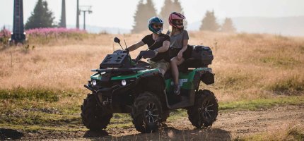 Ein Paar sitzt auf einem Quad auf einem Feldweg.