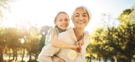 Oma mit Enkelkind auf dem Rücken