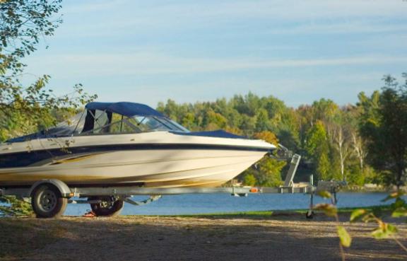 Bootsanhänger ohne Auto steht auf einer Wiese am See.