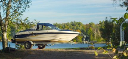 Bootsanhänger ohne Auto steht auf einer Wiese am See.
