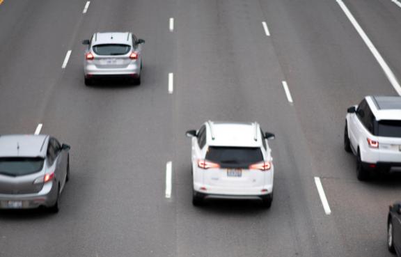 Eine Autobahn mit vier Fahrstreifen und fünf fahrenden Autos.