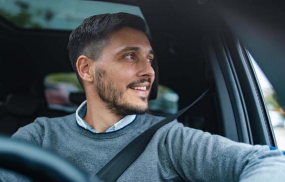 Eine Person sitzt im Auto und schaut aus dem Fenster, während sie den Sicherheitsgurt trägt.