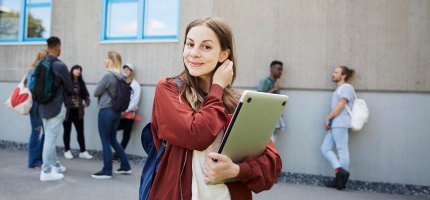 Schülerin steht vor einer Schule