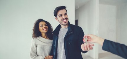 Glückliches Pärchen bei der Schlüsselübergabe für ihr Eigenheim