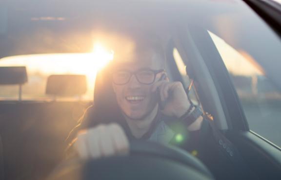 Mann telefoniert im Auto und lacht.