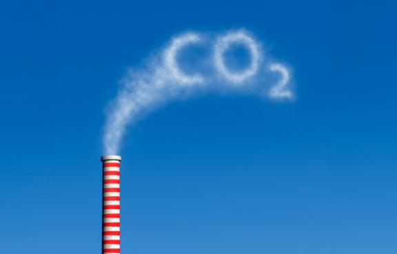 Ein Schlot bläst weißen Rauch aus, der den Begriff CO2 formt.