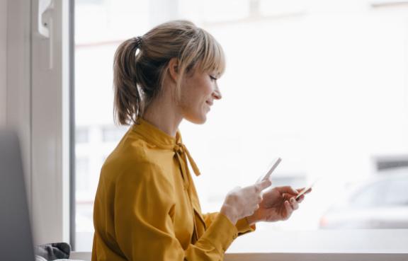  Eine Frau hält ihr Handy in der Hand und scannt Dokumente für ihren digitalen Führerschein.