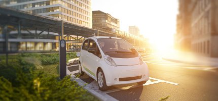 Elektroauto lädt in sonniger Stadt an der Strasse