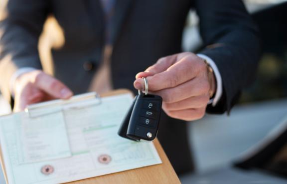 Autokauf, Verkäufer hält Zulassung Papiere und Schlüssel vor einer Reihe an Neuwagen