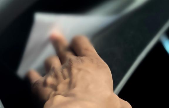 Eine Hand greift in das Handschuhfach eines Auto um Papiere herauszuholen.
