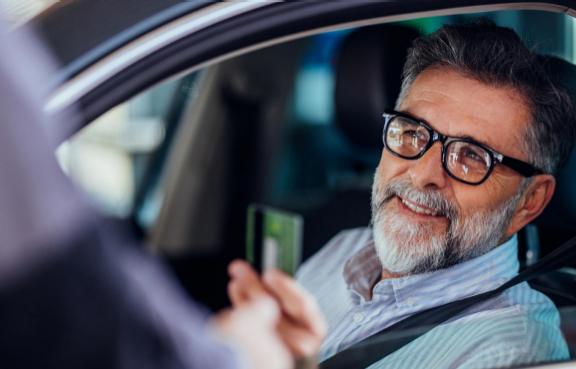 Ein älterer Mann mit Brille sitzt in einem Auto
