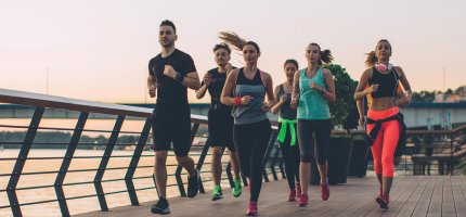 Eine Laufgruppe joggt am Wasser auf einem Steg.