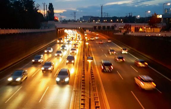 Eine dreispurige Autobahn mit fließendem Verkehr bei Nacht.