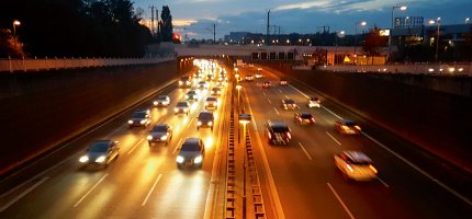 Eine dreispurige Autobahn mit fließendem Verkehr bei Nacht.