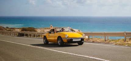 Gelbes Auto auf Straße am Meer