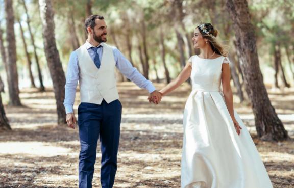 Hochzeitspaar geht Hand in Hand im Wald spazieren.