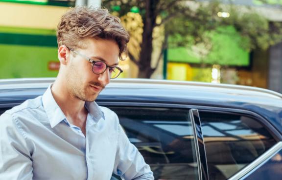 Junger Mann lehnt an seinem Auto