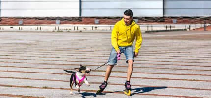 Ein Inline-Skater mit einem Hund an der Leine.